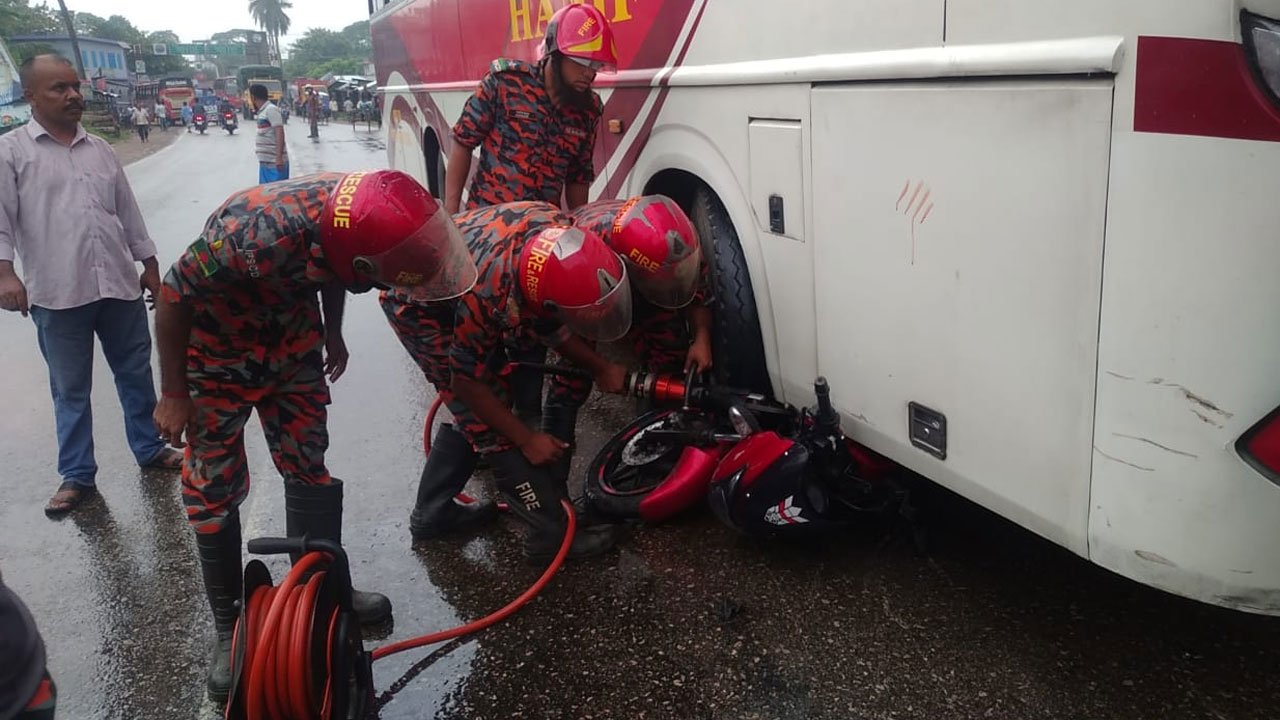 Fire service rescue workers are recovering an accident-hit motorcycle from under a bus.