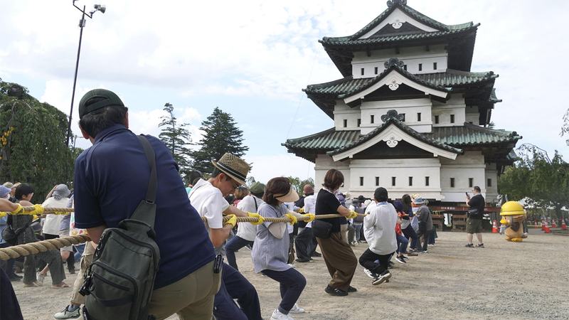 People-pull-on-ropes-attached-to-a-platform-carrying-the-Hirosaki-Castle