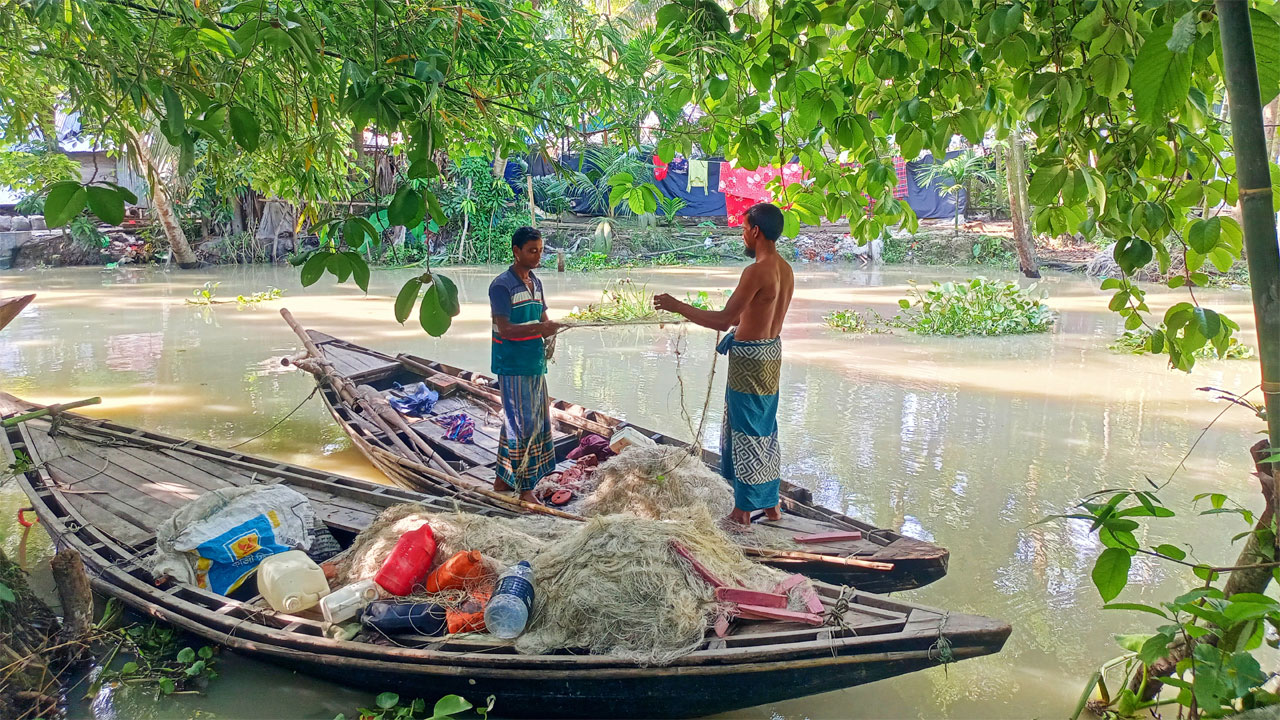নৌকায় বসে অলস সময় কাটাচ্ছেন দুুই জেলে