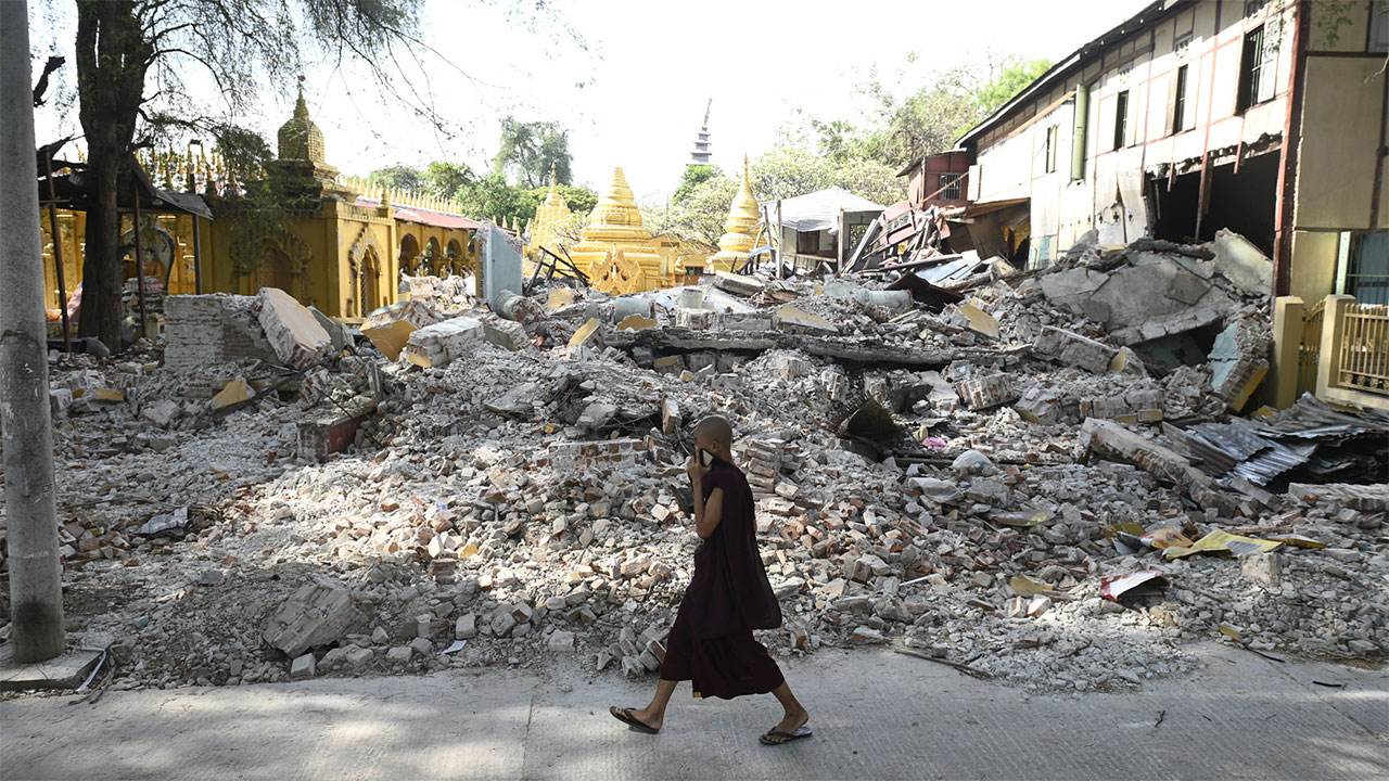 মান্দালয়ে ভূমিকম্পে ধসে পড়া ভবনের পাশ দিয়ে হেঁটে যাচ্ছেন একজন বৌদ্ধ ভিক্ষু