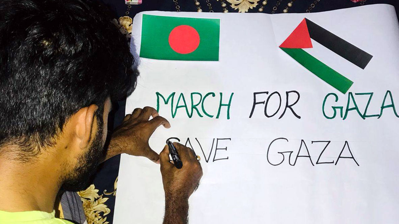 হতে লিখে পোস্টার তৈরি করছেন এক ব্যক্তি