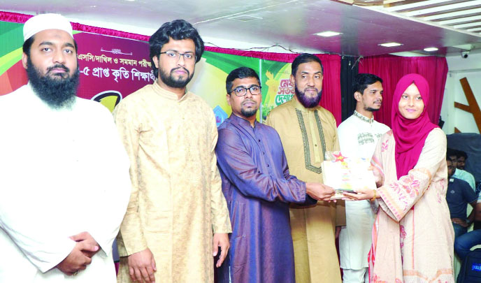 কৃতী শিক্ষার্থীর হাতে ক্রেস্ট ও উপহার তুলে দিচ্ছেন নূরুল ইসলাম : নয়া দিগন্ত