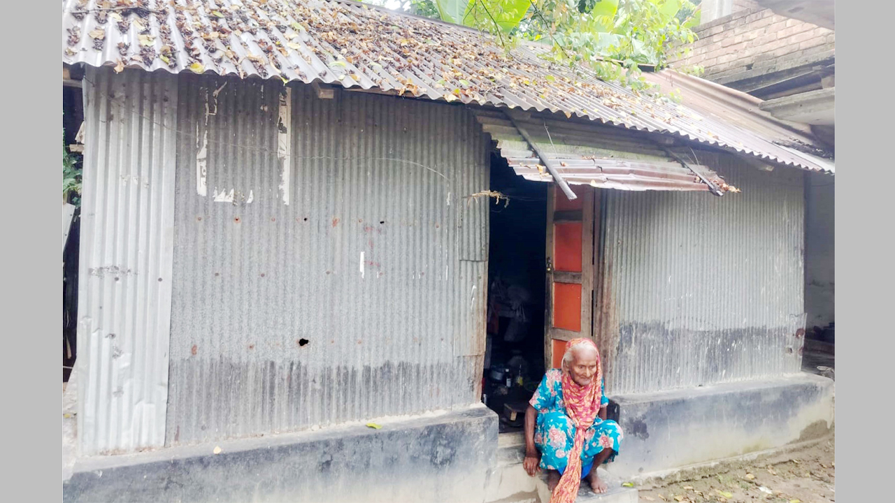 নিজ ঘরের সামনে বসে আছেন শতবর্ষী বৃদ্ধা সোনাভানু