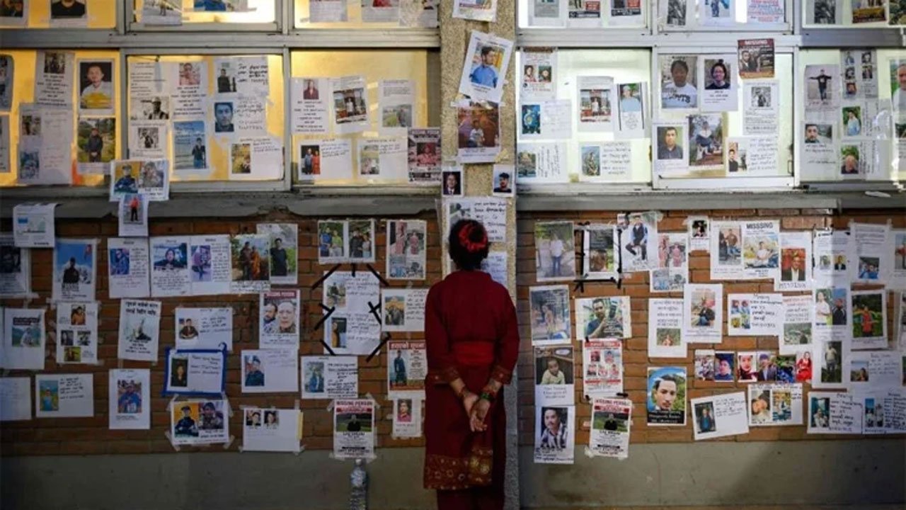 বন্যায় নিখোঁজ ব্যক্তিদের ছবি দেখছেন এক নারী