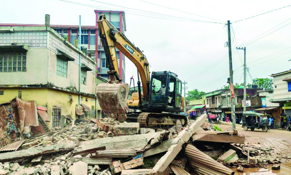 পাইকগাছার কপিলমুনিতে এক্সক্যাভেটর দিয়ে একটি দ্বিতল ভবন ভেঙে ফেলা হচ্ছে : নয়া দিগন্ত