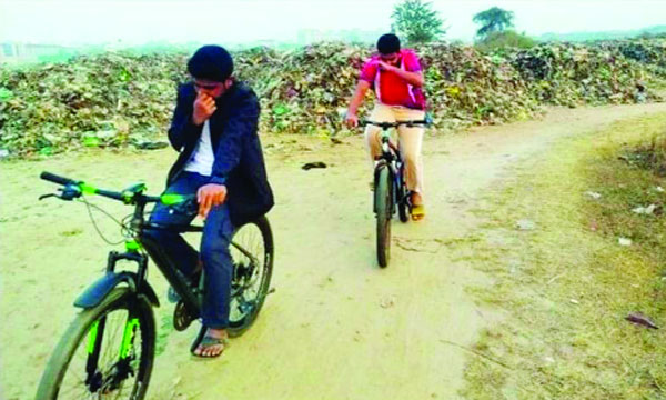 ভাগাড়ের পাশ দিয়ে নাক চেপে যাচ্ছে দুই সাইকেল আরোহী