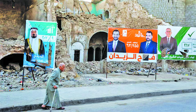 আসন্ন সংসদ নির্বাচনের আগে ইরাকের মসুলে রাস্তায় লাগানো ইরাকি সংসদীয় প্রার্থীদের প্রচারণার পোস্টারের পাশ দিয়ে হেঁটে যাচ্ছেন এক ব্যক্তি : ইন্টারনেট